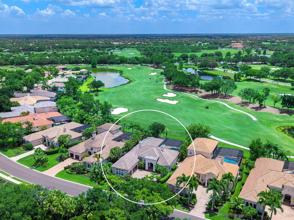 An aerial view shows a residential house with a tiled roof surrounded by lush landscaping — 7431 GREYSTONE STREET, LAKEWOOD RANCH, FL