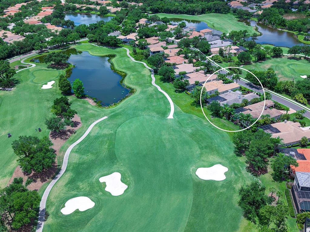 An aerial view shows a residential neighborhood bordering a golf course with a large pond — 7431 GREYSTONE STREET, LAKEWOOD RANCH, FL