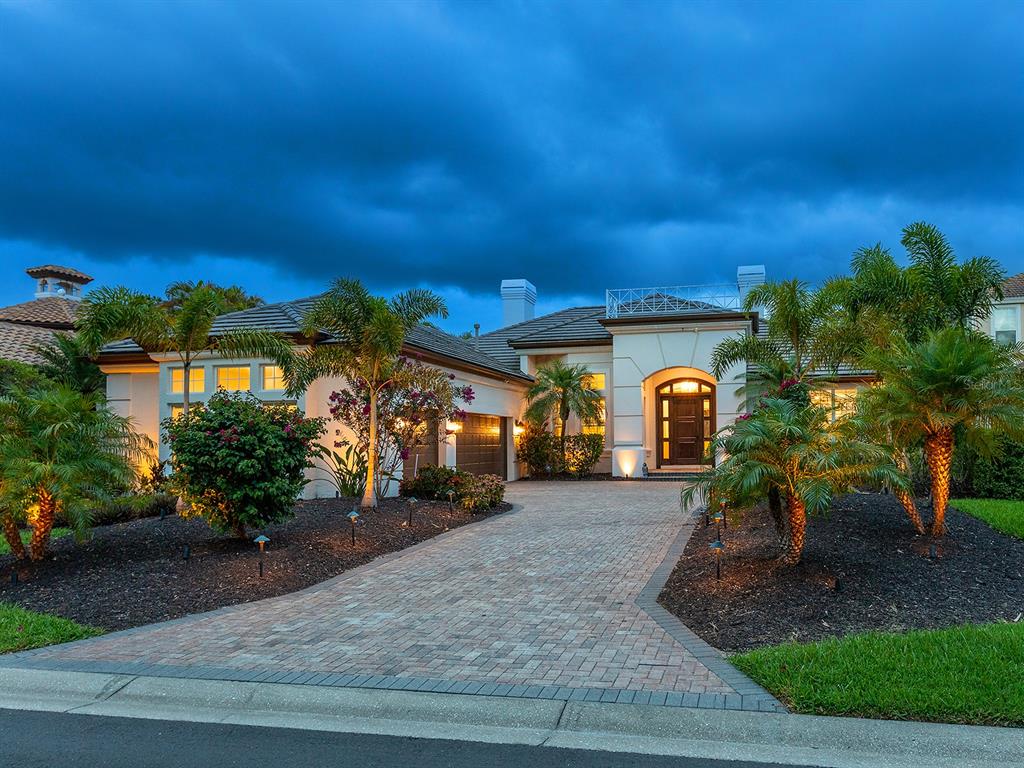 A single-story house with a paved driveway, palm trees, and a dark wood front door — 7431 GREYSTONE STREET, LAKEWOOD RANCH, FL