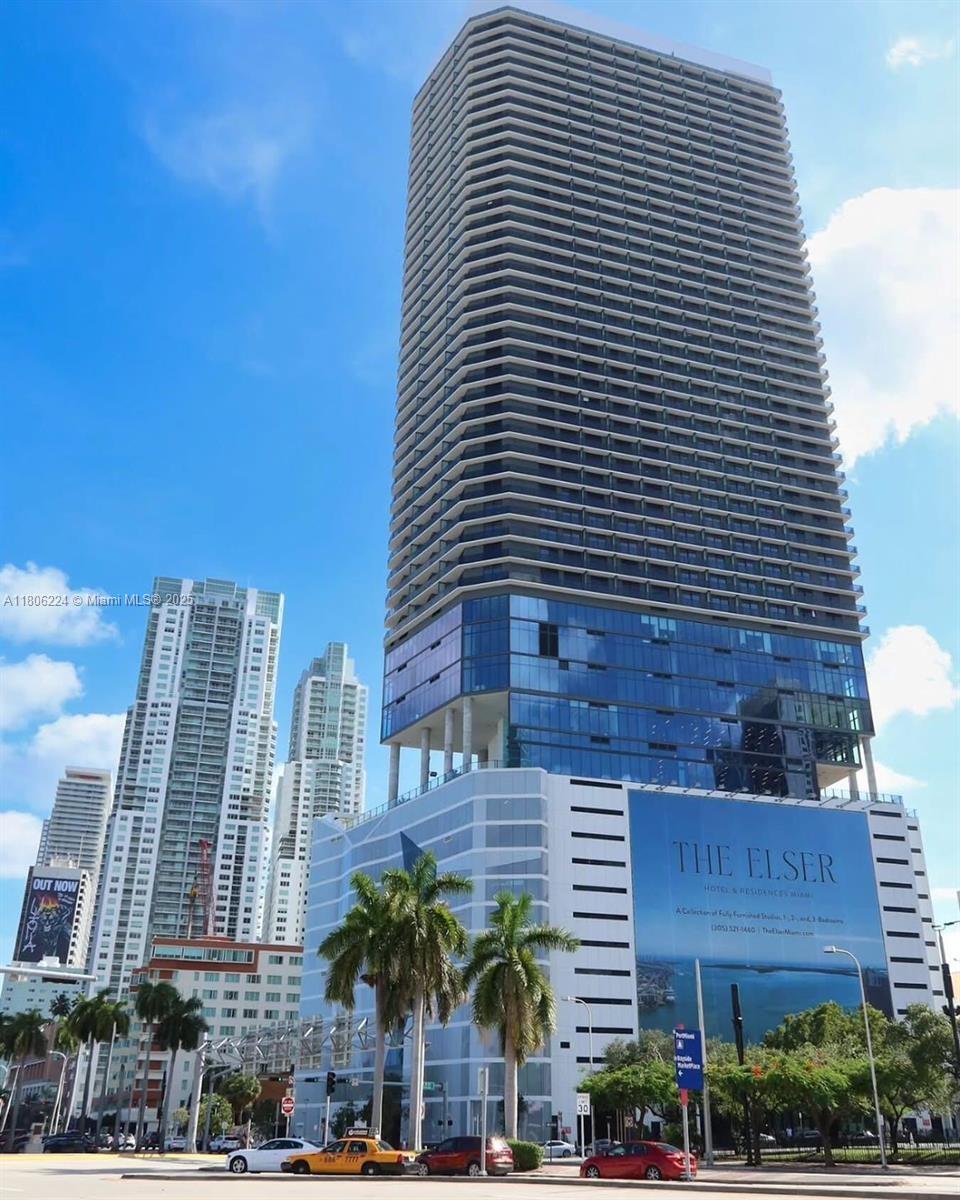 A tall, modern high-rise building with a glass facade and balconies stands in an urban area — 398 NE 5th St # 1619, Miami FL 33132, MIAMI, FL