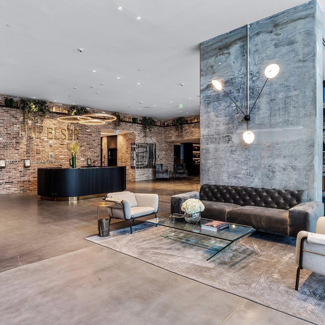 A modern lobby features a brick wall, a concrete pillar, and contemporary lounge seating — 398 NE 5th St # 1619, Miami FL 33132, MIAMI, FL