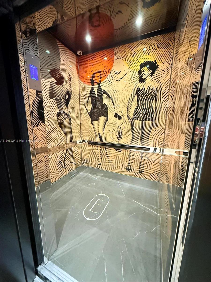 An elevator interior features decorative wall panels with stylized figures and a marble floor — 398 NE 5th St # 1619, Miami FL 33132, MIAMI, FL