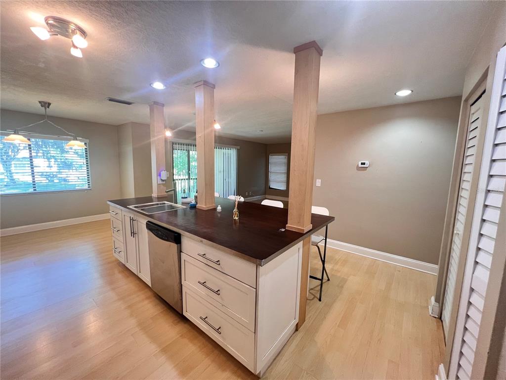 A kitchen island with a dark countertop and white cabinets sits between two wooden support columns — 302 PALM COAST PARKWAY NE UNIT 204, PALM COAST, FL