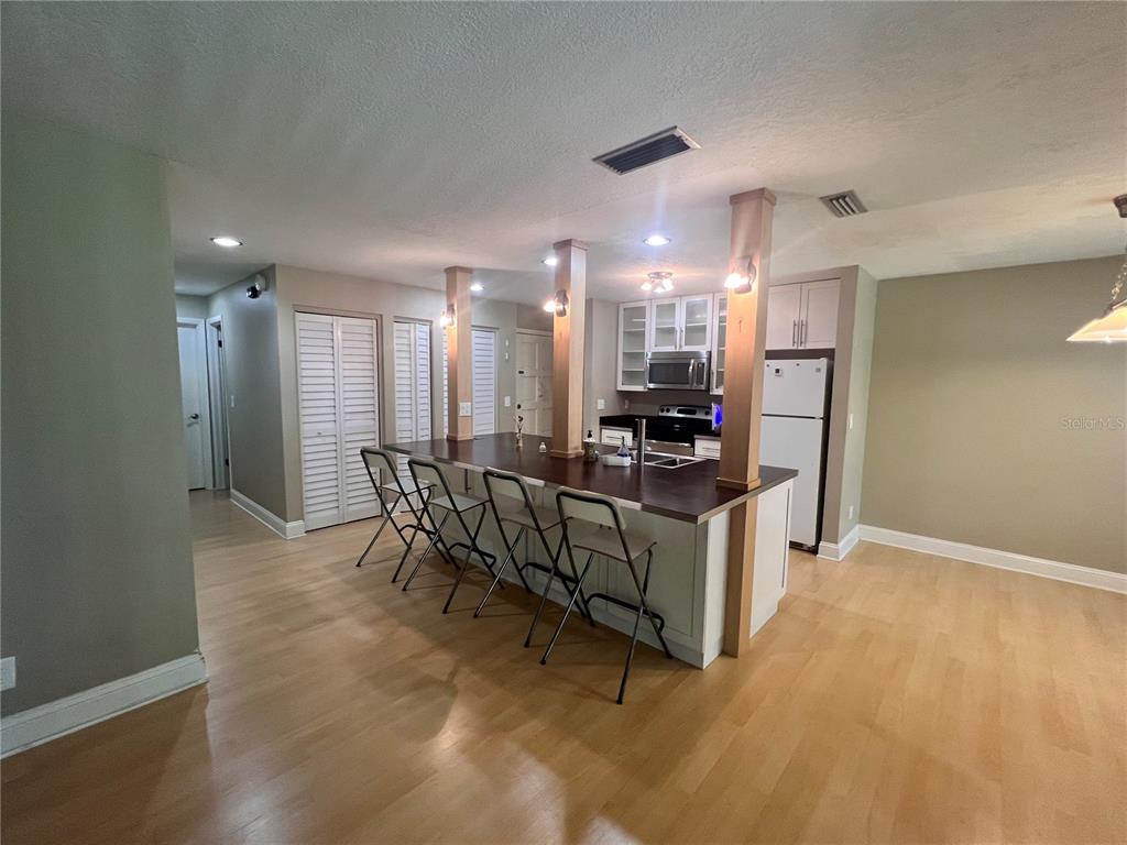 A kitchen features a dark wood breakfast bar with four folding chairs and light flooring — 302 PALM COAST PARKWAY NE UNIT 204, PALM COAST, FL