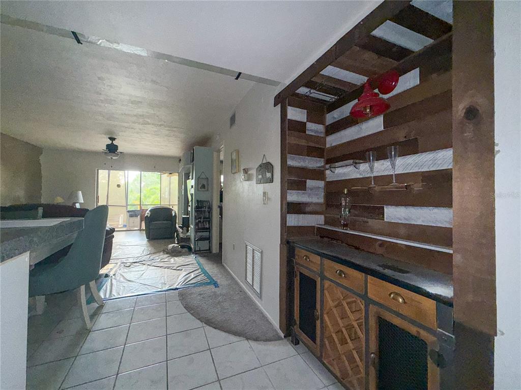 A dining area features a rustic wood-paneled built-in bar and tile flooring — 6800 PLACIDA ROAD UNIT 144, ENGLEWOOD, FL