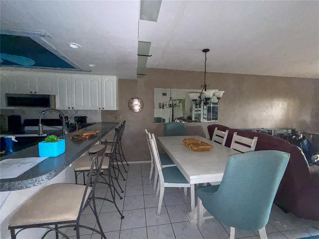 A dining area with a white table and chairs sits adjacent to a kitchen counter — 6800 PLACIDA ROAD UNIT 144, ENGLEWOOD, FL
