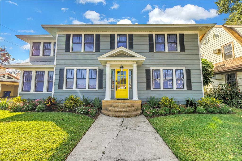 A two-story blue house features a bright yellow front door and a concrete walkway — 2320 5TH STREET N, ST PETERSBURG, FL