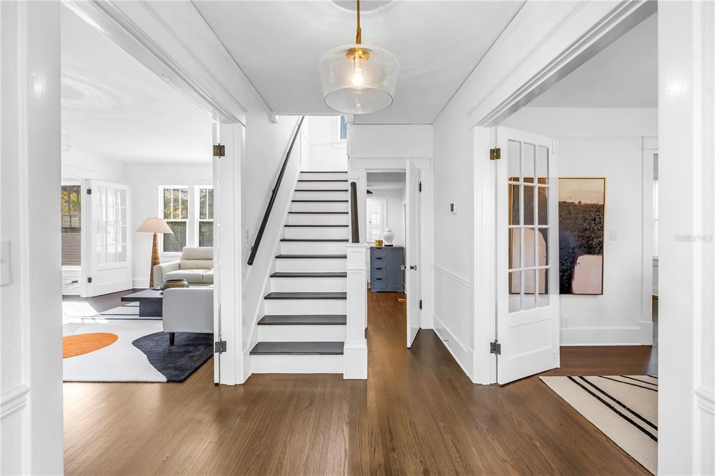A bright foyer features hardwood floors, a central staircase, and glass-paneled doors leading to adjacent rooms — 2320 5TH STREET N, ST PETERSBURG, FL