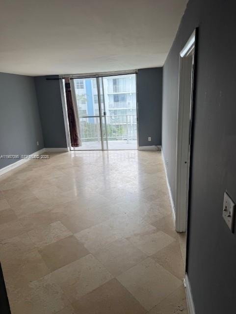 An empty room features light-colored tile flooring, gray walls, and a sliding glass door balcony entrance — 488 NW 165th St Rd # 408, Miami FL 33169, MIAMI, FL