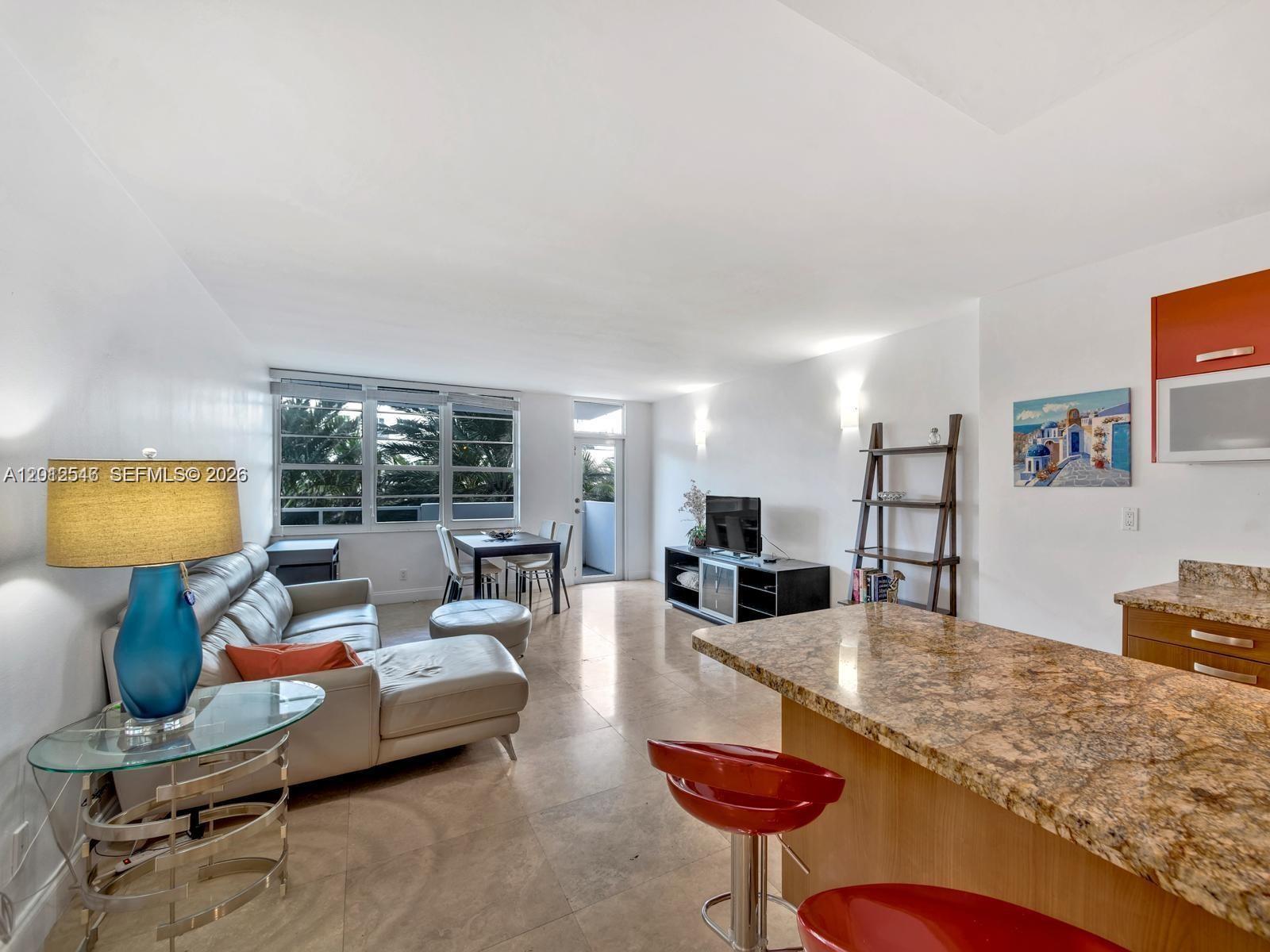 This open-concept living area features tile flooring, a kitchen island, and a dining space — 100 Lincoln Rd # 308, Miami Beach FL 33139, MIAMI BEACH, FL