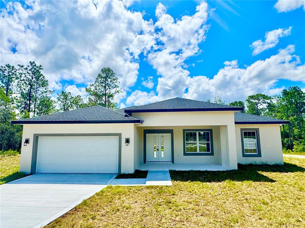 A single-story house with a white stucco exterior, a two-car garage, and a covered entryway — 9835 N ESSEX TERRACE, DUNNELLON, FL