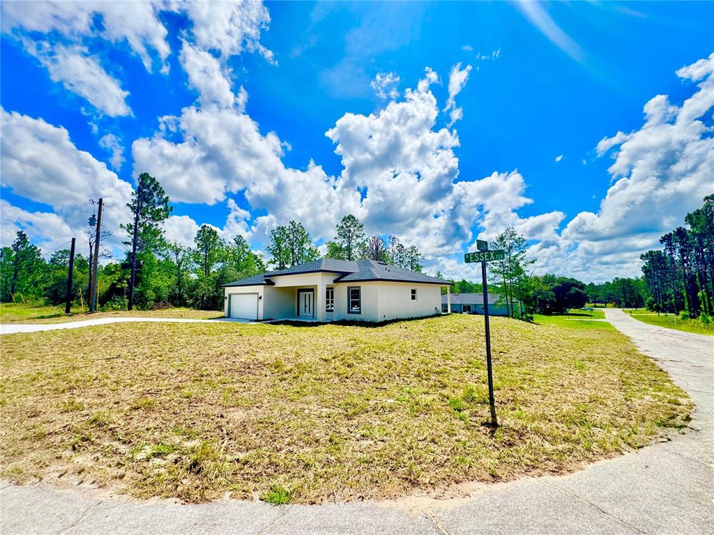 A modern single-story house with a white exterior and garage sits on a grassy lot — 9835 N ESSEX TERRACE, DUNNELLON, FL