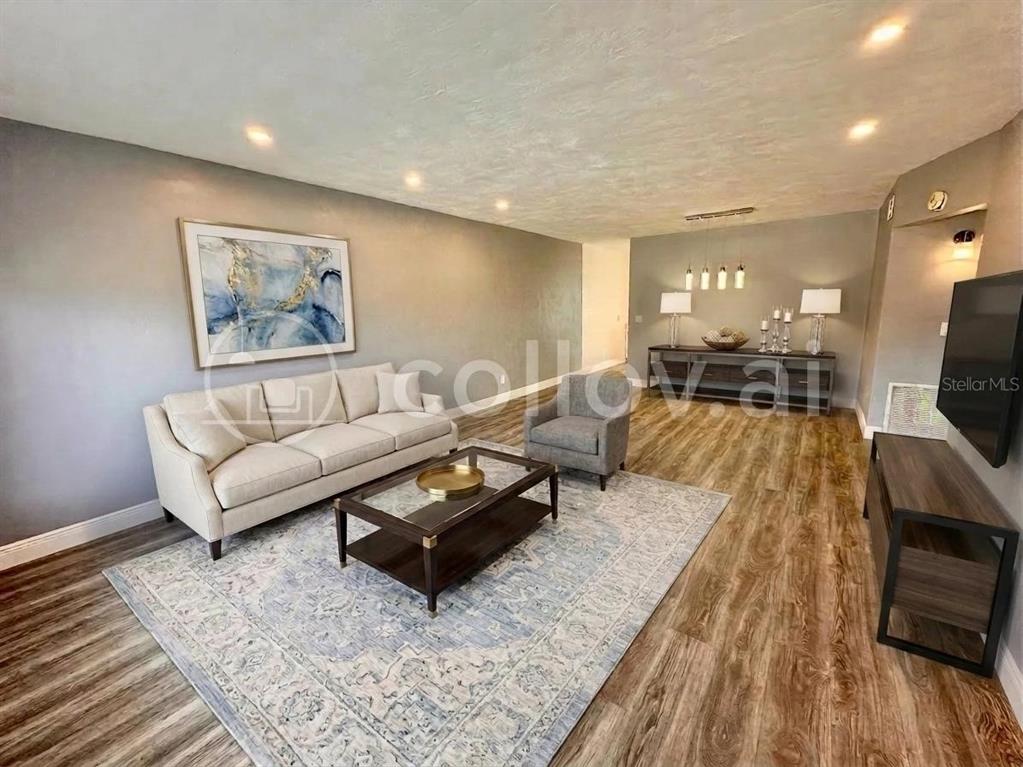 A living room features light wood flooring, a beige sofa, a glass coffee table, and area rug — 2431 CANADIAN WAY UNIT 37, CLEARWATER, FL