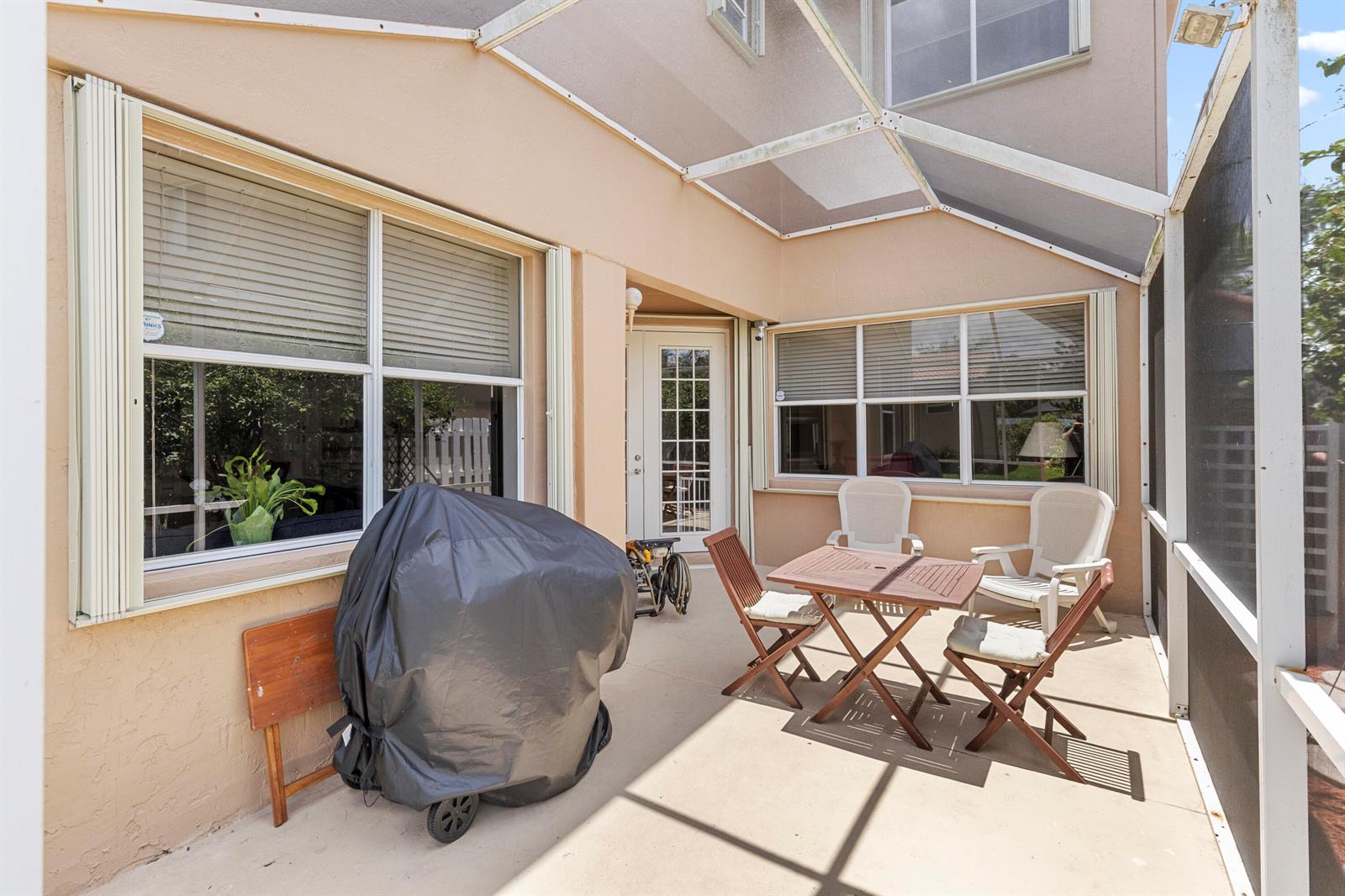 A covered patio features a grill, a wooden table with chairs, and large windows — 907 Stanton Drive, Weston FL 33326, WESTON, FL