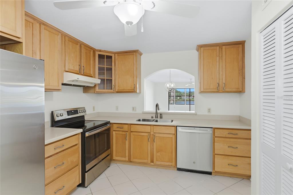 A kitchen with light wood cabinets, stainless steel appliances, and a pass-through window — 211 LAKEWOOD DRIVE UNIT 211, BRADENTON, FL