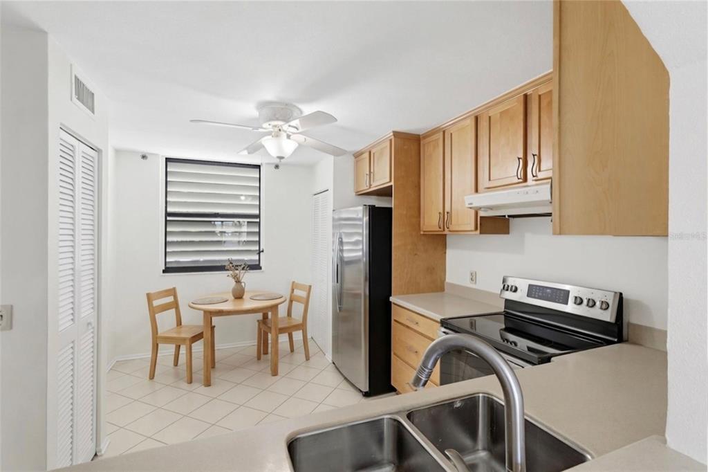 A kitchen with light wood cabinets, stainless steel appliances, and a small dining area — 211 LAKEWOOD DRIVE UNIT 211, BRADENTON, FL