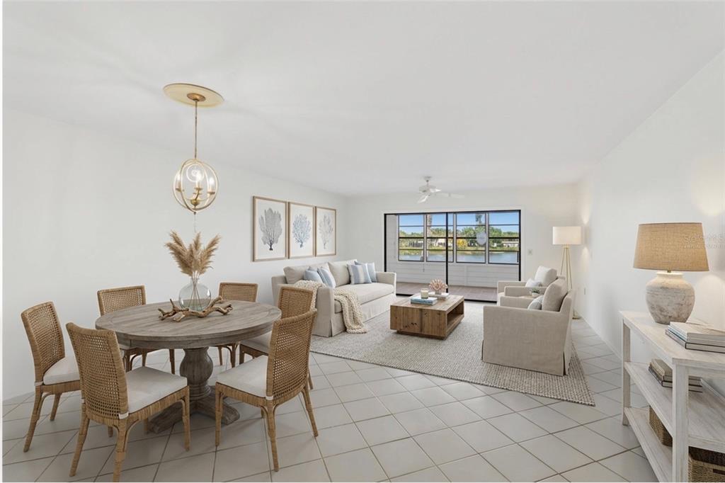 A bright living and dining area with tile floors, neutral furniture, and a waterfront view — 211 LAKEWOOD DRIVE UNIT 211, BRADENTON, FL