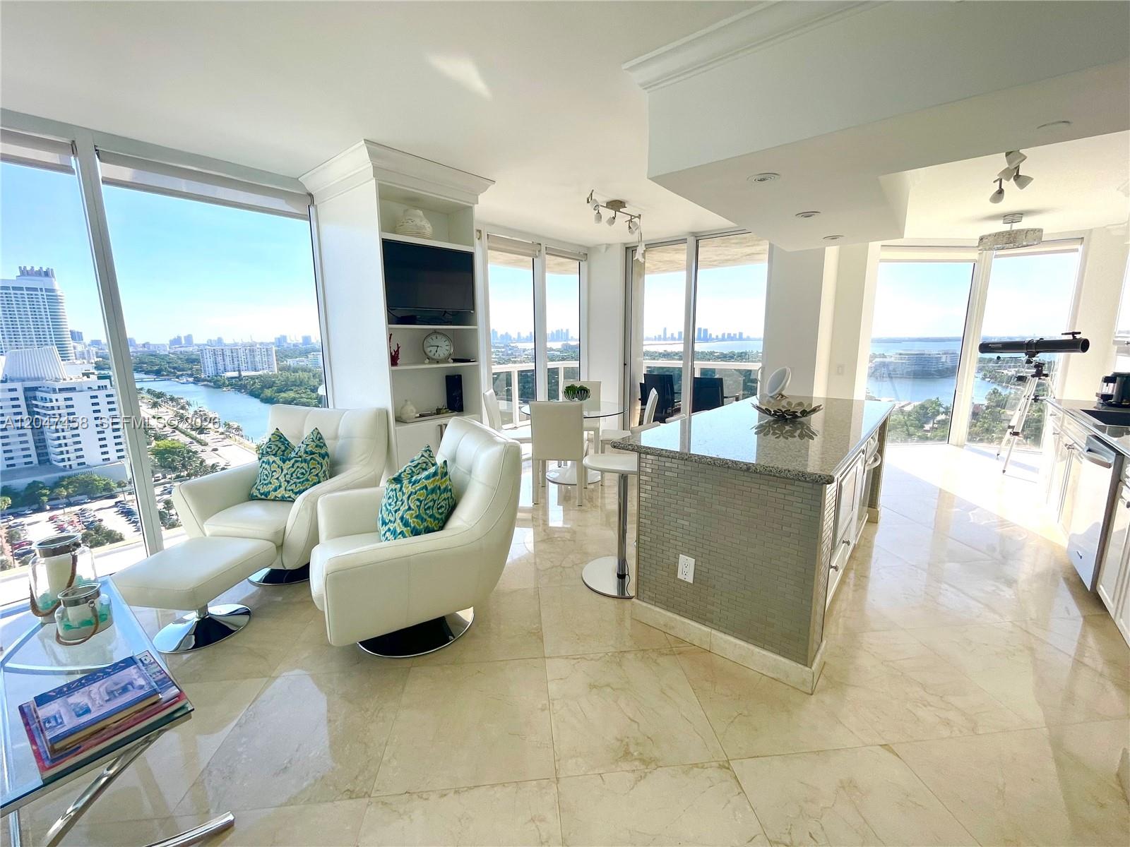 A bright, open-concept living and kitchen area features floor-to-ceiling windows with panoramic water views — 4775 Collins Ave # 2305, Miami Beach FL 33140, MIAMI BEACH, FL