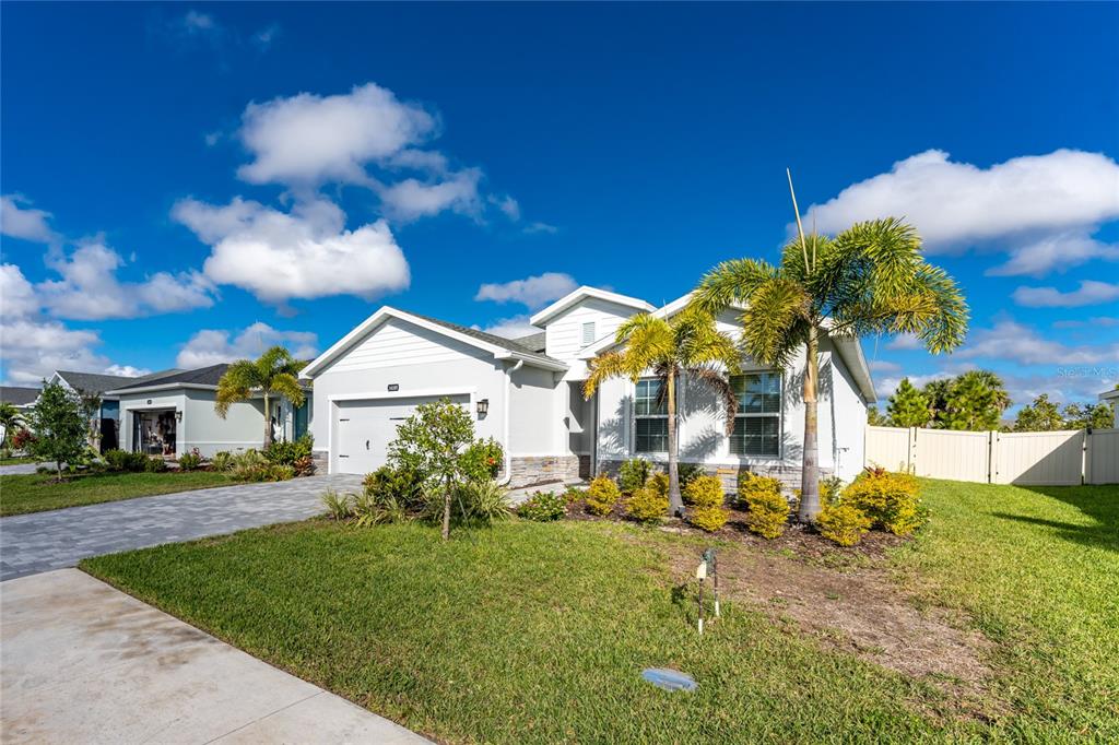 A single-story house with a paved driveway, palm trees, and a white garage door — 16185 S PORT HARBOR BOULEVARD, PORT CHARLOTTE, FL
