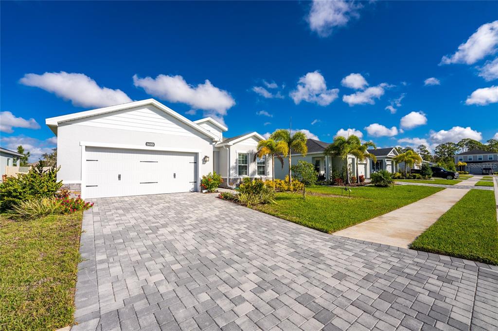 A single-story house with a white garage and paver driveway under a blue sky — 16185 S PORT HARBOR BOULEVARD, PORT CHARLOTTE, FL