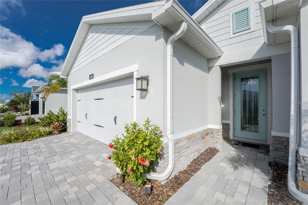 The exterior of a house features a white garage, stone accents, and a light blue door — 16185 S PORT HARBOR BOULEVARD, PORT CHARLOTTE, FL