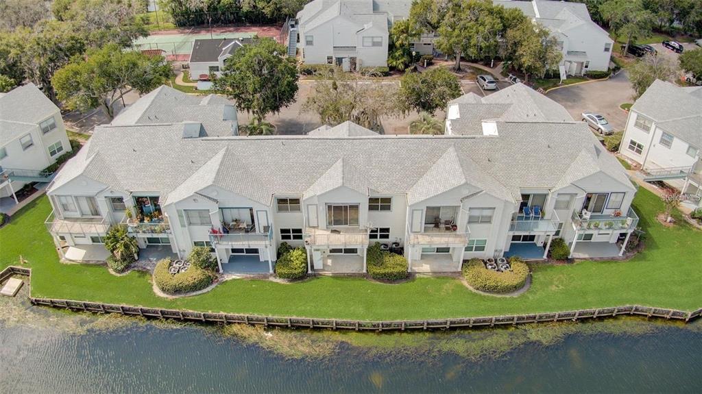 An aerial view of a multi-unit residential building with balconies overlooking a pond — 2556 WOODGATE BOULEVARD UNIT 101, ORLANDO, FL