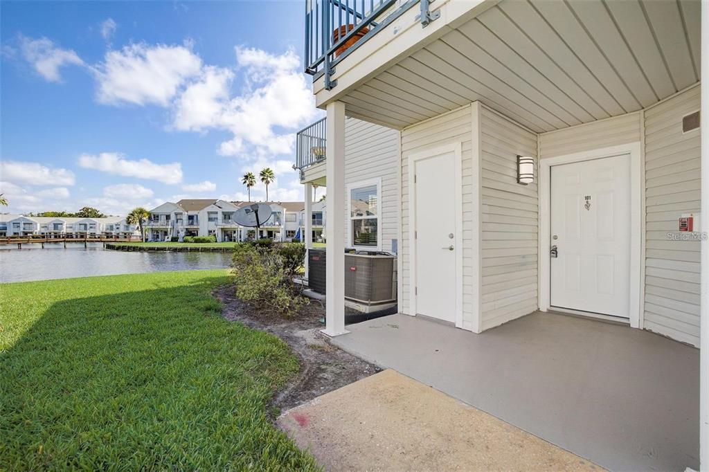 An exterior view of a ground-level apartment entrance with a patio, siding, and water view — 2556 WOODGATE BOULEVARD UNIT 101, ORLANDO, FL