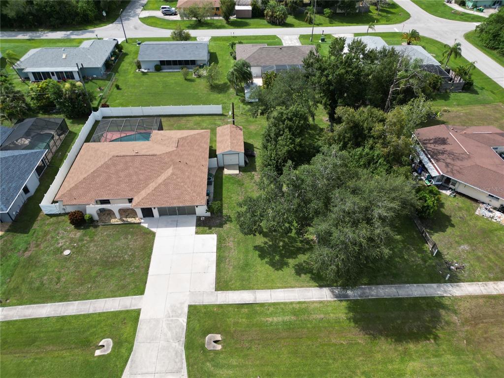 An aerial view shows a house with a pool, a detached shed, and large trees — 19842 MIDWAY BLVD, PORT CHARLOTTE, FL