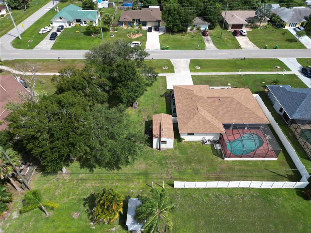 An aerial view shows a house with a pool, a detached shed, and large trees — 19842 MIDWAY BLVD, PORT CHARLOTTE, FL