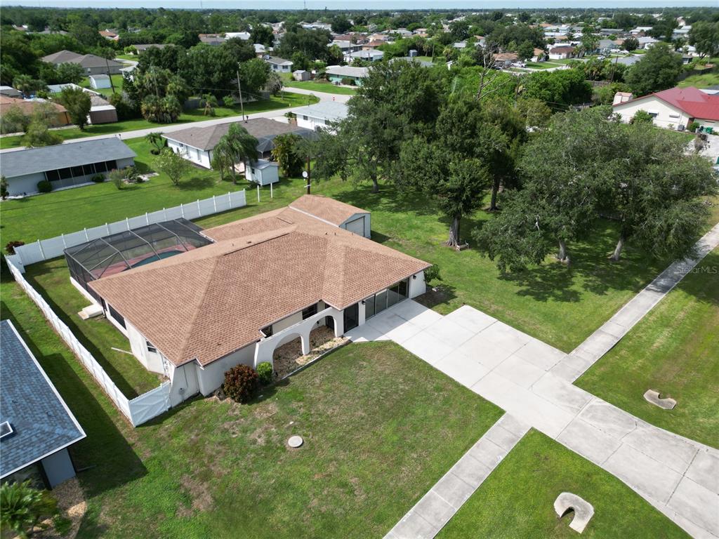 An aerial view shows a single-story house with a pool enclosure and a large yard — 19842 MIDWAY BLVD, PORT CHARLOTTE, FL