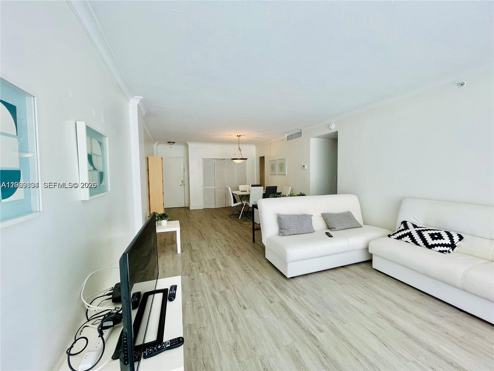 A living room features light wood-look flooring, white walls, and two white sofas — 3001 S Ocean Dr # 101, Hollywood FL 33019, HOLLYWOOD, FL