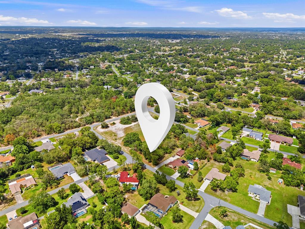An aerial view shows a residential neighborhood with a large white location pin marker — 1228 STATEN AVENUE, SPRING HILL, FL