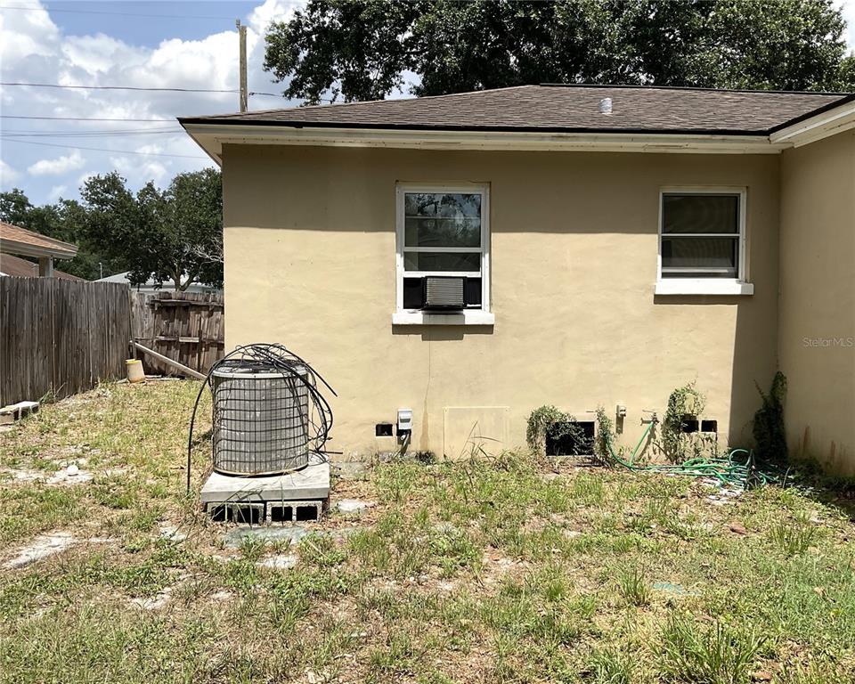 The exterior of a house features a tan stucco wall, two windows, and an AC unit — 416 CRABTREE AVENUE, ORLANDO, FL