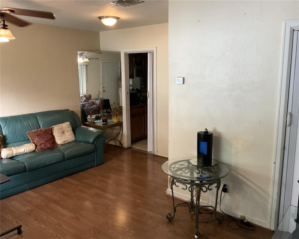 A living room features a teal leather sofa, wood-look flooring, and a glass-topped side table — 416 CRABTREE AVENUE, ORLANDO, FL
