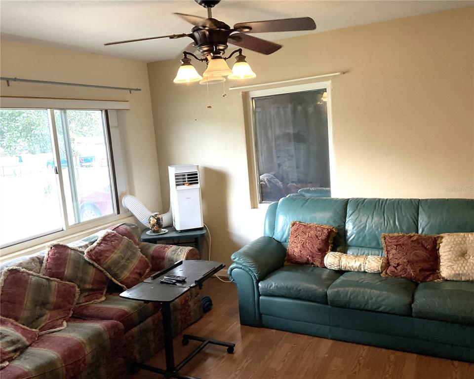 A living room features a green leather sofa, a patterned sofa, and a portable air conditioner — 416 CRABTREE AVENUE, ORLANDO, FL