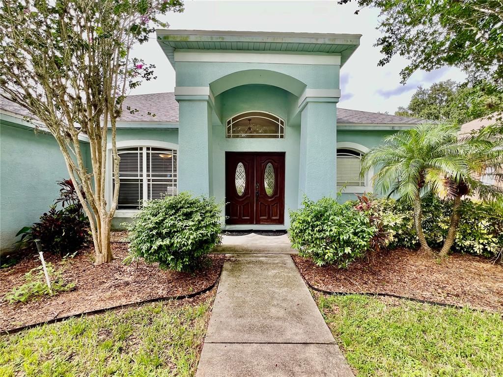 The front exterior of a light blue house features a double door entrance and landscaping — 2848 DUNCAN TREE CIRCLE, VALRICO, FL