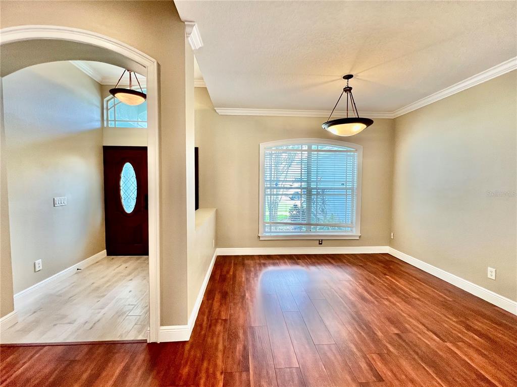 A dining room with dark wood flooring, a chandelier, and an arched entryway — 2848 DUNCAN TREE CIRCLE, VALRICO, FL