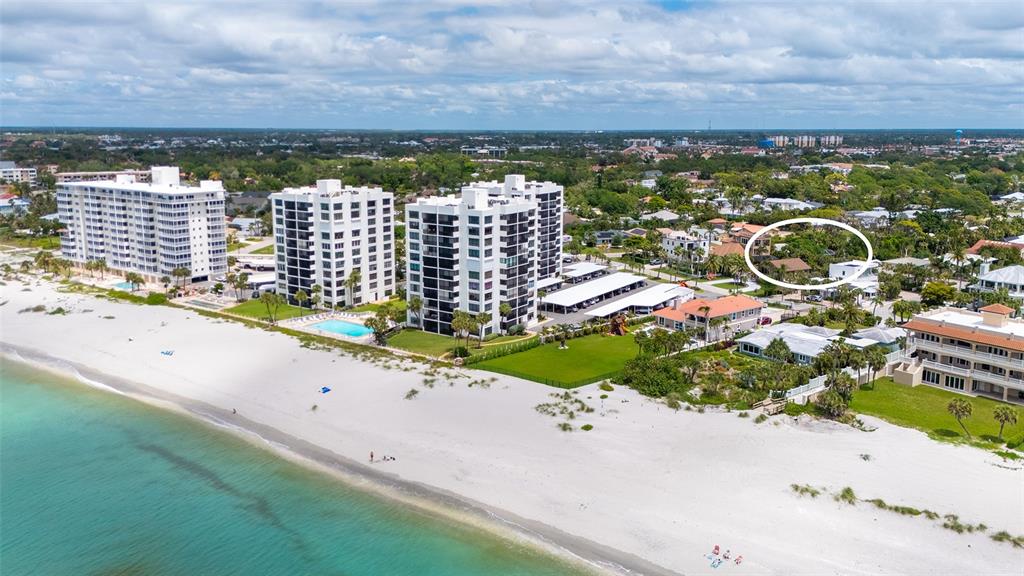 An aerial view shows a sandy beach, three high-rise condominiums, and surrounding residential properties — 621 ALHAMBRA ROAD, VENICE, FL