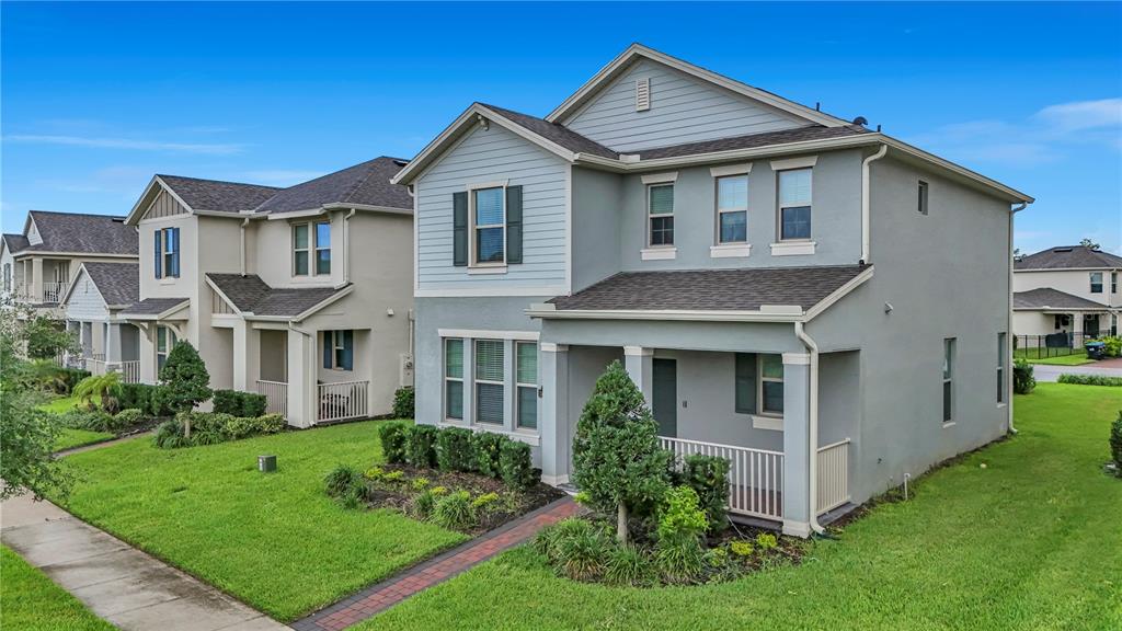 A two-story house with light blue siding, a covered front porch, and a green lawn — 16495 POINT ROCK DRIVE, WINTER GARDEN, FL