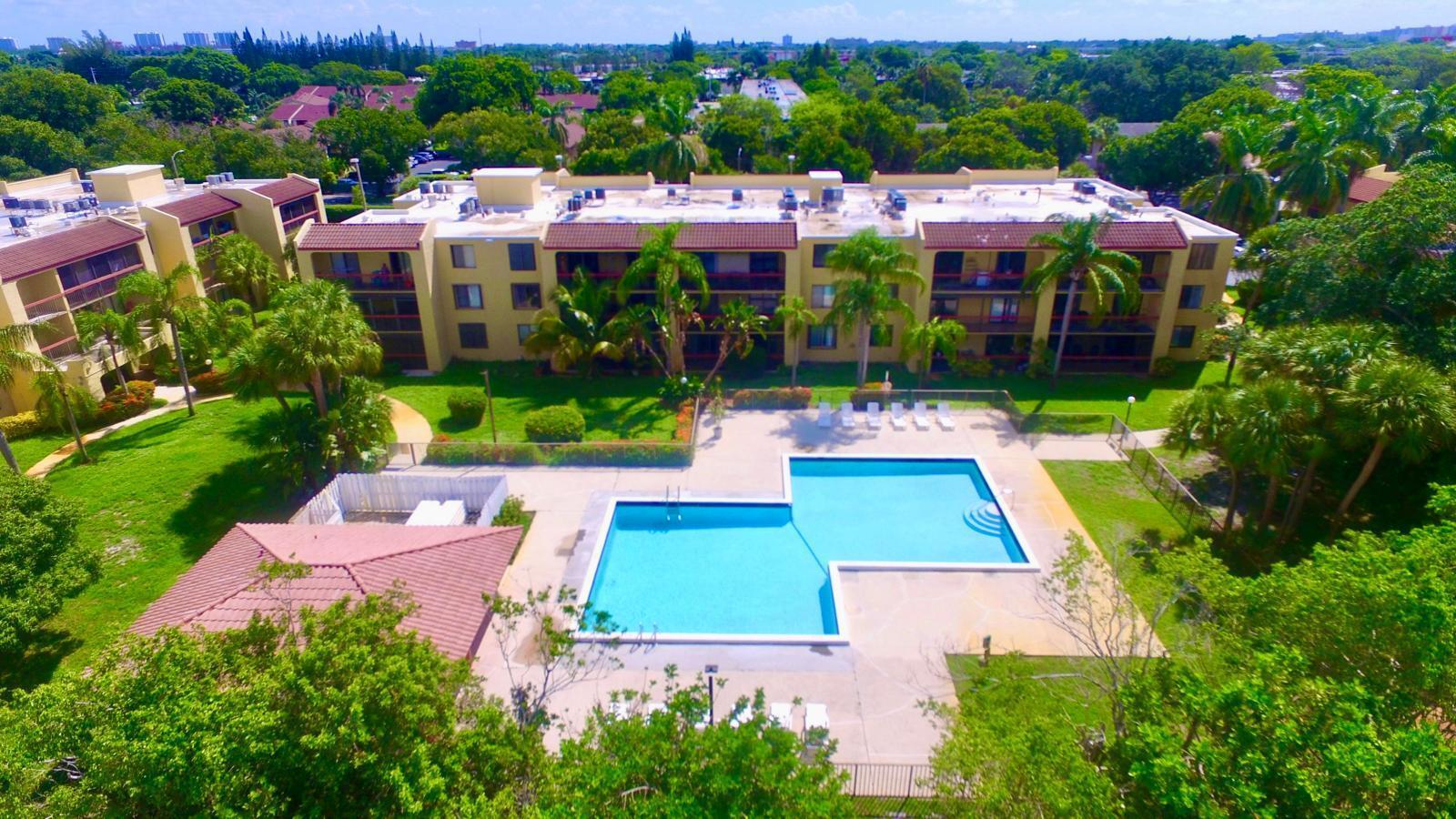 An aerial view of an apartment complex with a swimming pool and surrounding palm trees — 737 SE 1st Way # 306, Deerfield Beach FL 33441, DEERFIELD BEACH, FL
