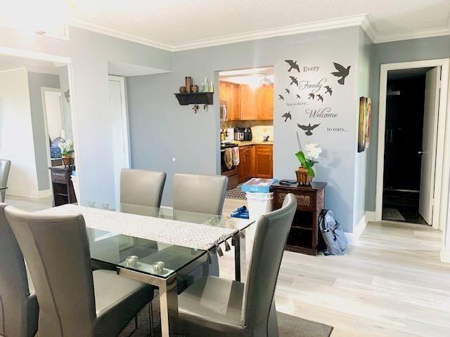 A dining room features a glass table, gray chairs, and a wall decal near a kitchen — 737 SE 1st Way # 306, Deerfield Beach FL 33441, DEERFIELD BEACH, FL