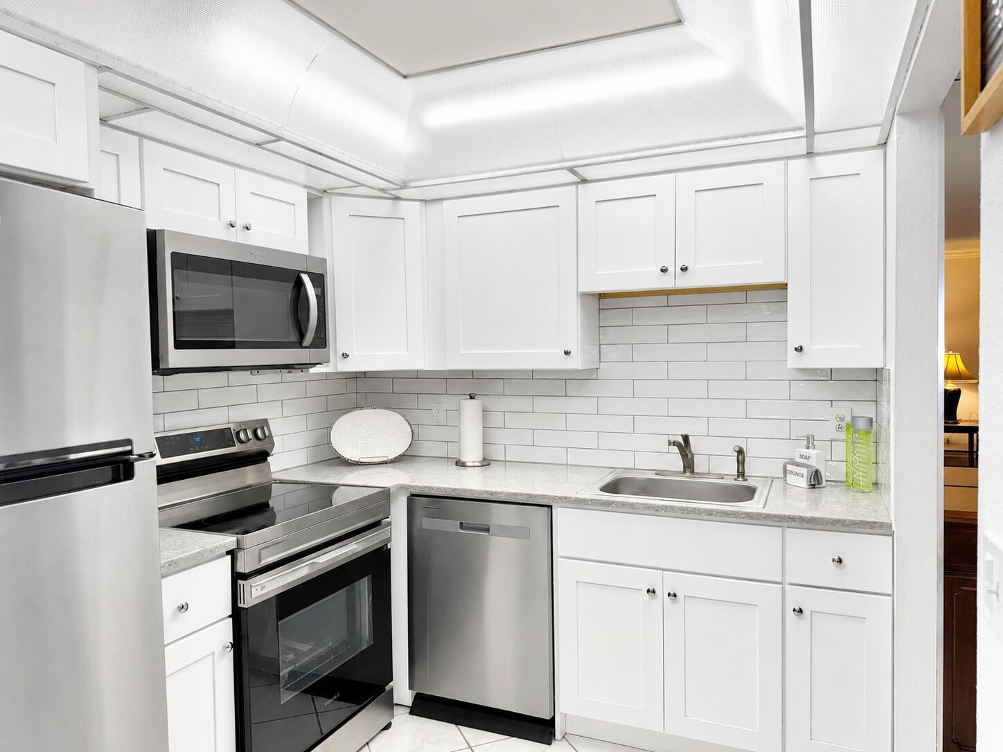 A kitchen with white cabinets, stainless steel appliances, granite countertops, and a white subway tile backsplash — 6 Brittany A # 6a, Delray Beach FL 33446, DELRAY BEACH, FL