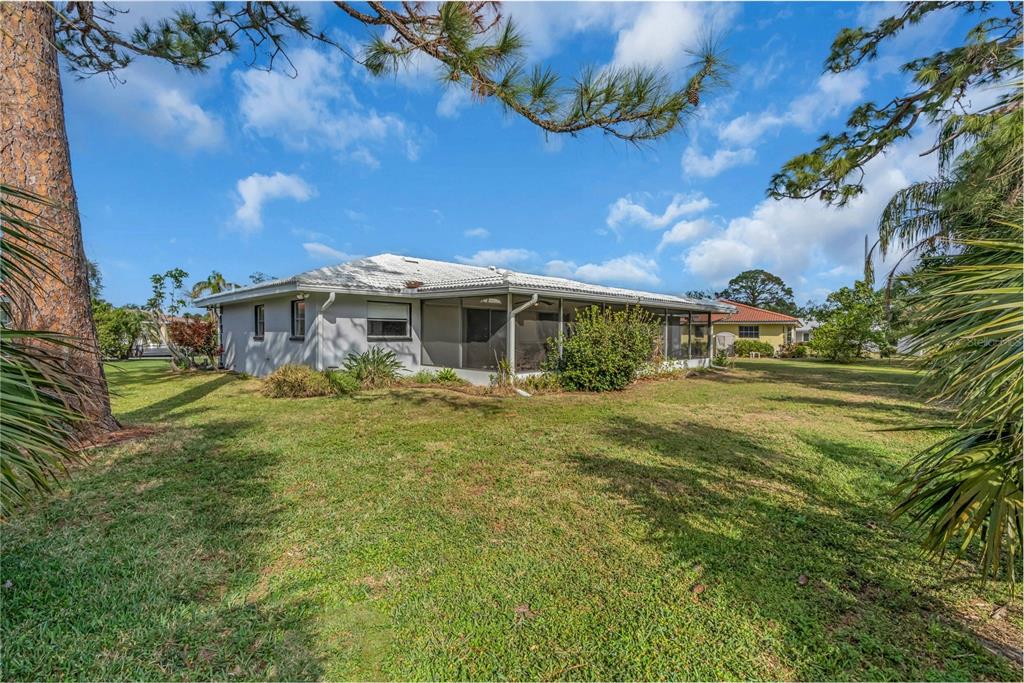 The exterior of a single-story house with a screened-in porch and a grassy backyard — 2544 CARLISLE PLACE, SARASOTA, FL