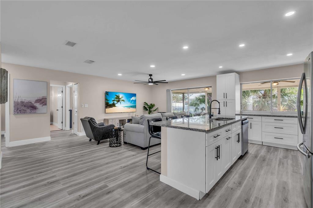 An open-concept kitchen and living area featuring white cabinets, granite countertops, and gray flooring — 2544 CARLISLE PLACE, SARASOTA, FL