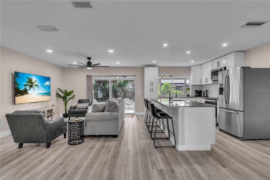 An open-concept living room and kitchen featuring light wood flooring and a kitchen island — 2544 CARLISLE PLACE, SARASOTA, FL