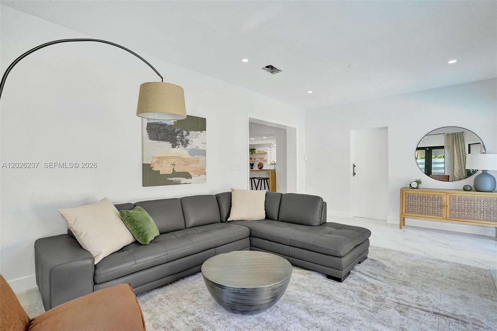A living room features a grey sectional sofa, a round coffee table, and a floor lamp — 1355 Madison St, Hollywood FL 33019, HOLLYWOOD, FL