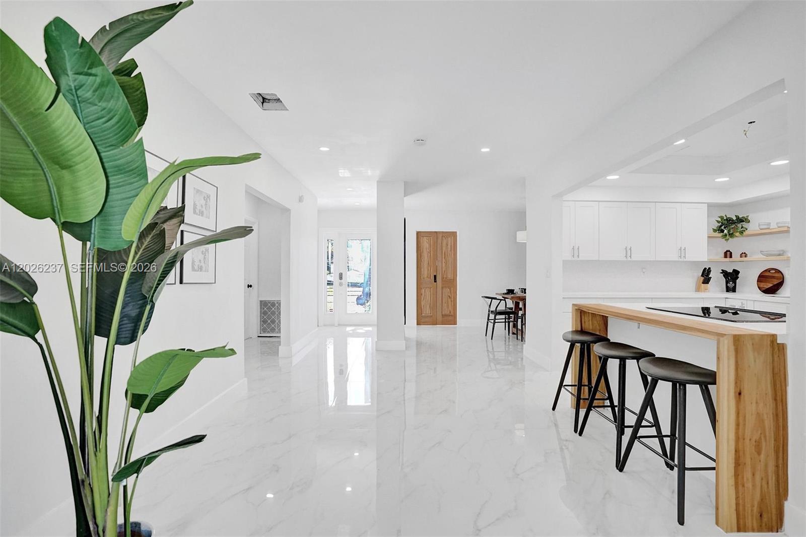 A bright, open-concept kitchen and living area features white cabinetry, marble floors, and bar seating — 1355 Madison St, Hollywood FL 33019, HOLLYWOOD, FL