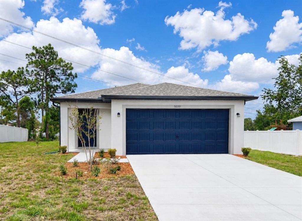 A single-story house with a white exterior, blue garage door, and a concrete driveway — 5220 WENDAL STREET, SPRING HILL, FL