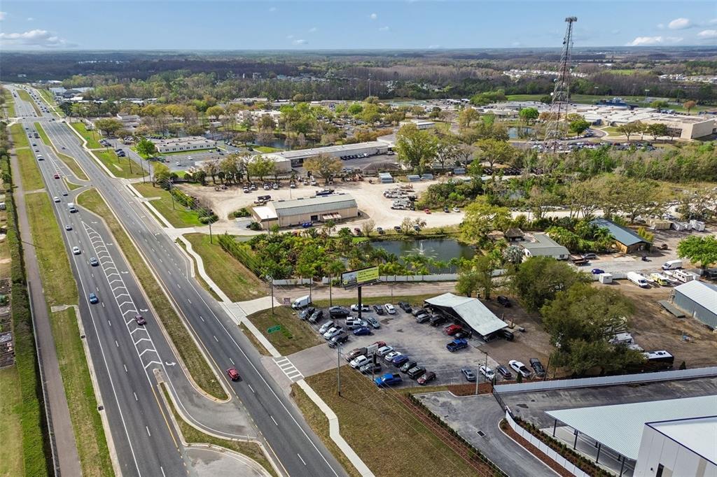 An aerial view shows a multi-lane highway adjacent to a commercial property with parking lots — 7411 LAND O LAKES BOULEVARD, LAND O LAKES, FL