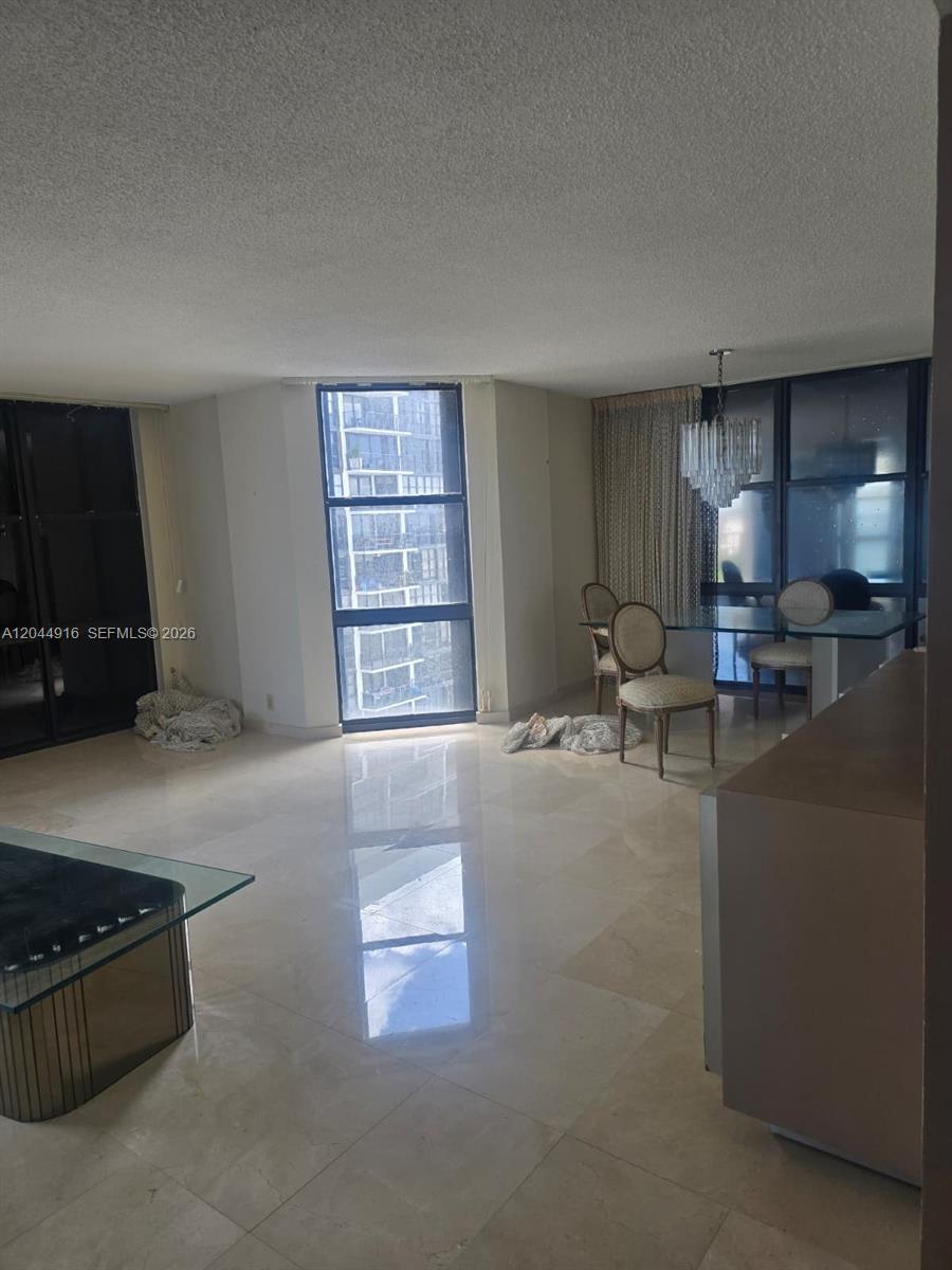 A dining and living area features marble floors, floor-to-ceiling windows, and a crystal chandelier — 1901 Brickell Ave # B1614, Miami FL 33129, MIAMI, FL